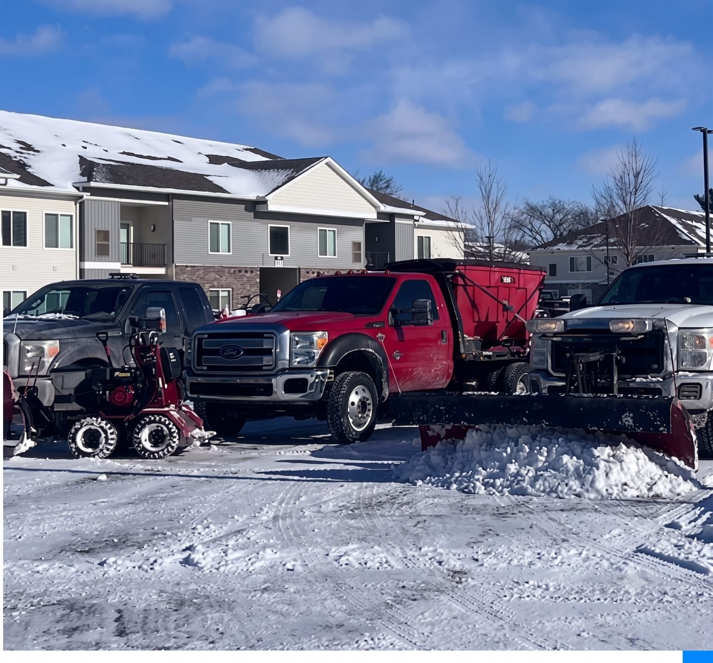 Plow and salt trucks clearing a residential complex driveway